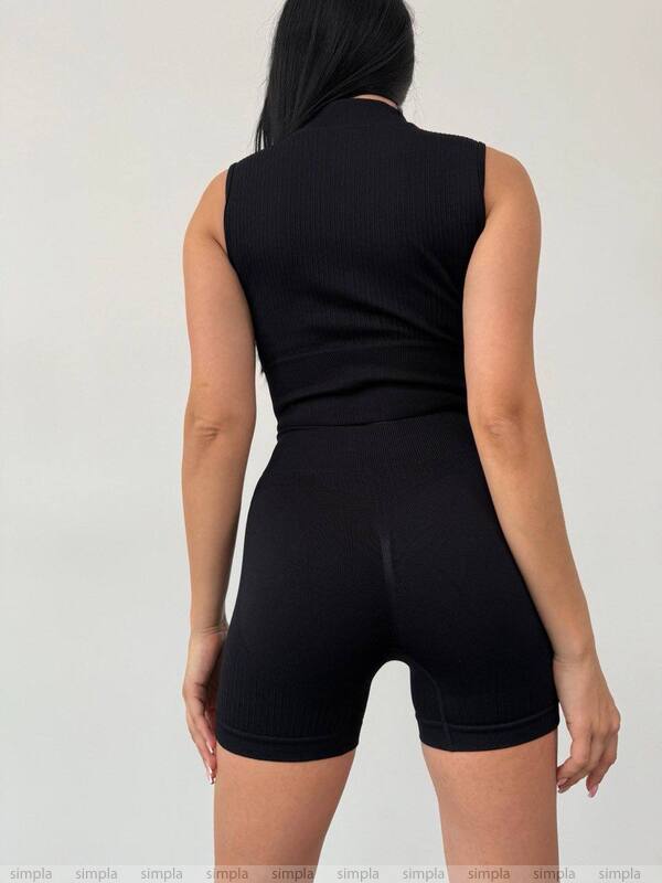 Person wearing a black sleeveless top and shorts set on a plain background