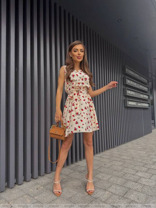 Woman in a floral dress standing against a modern building exterior.