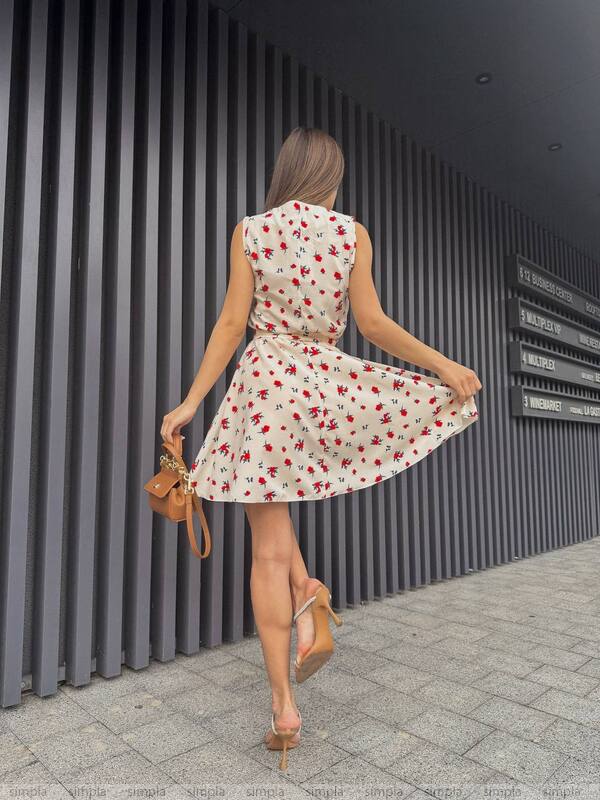 Woman in a floral dress twirling in front of a modern building.