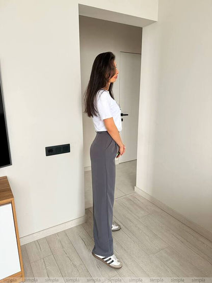Person standing in a minimalistic room with white walls and light wood flooring.