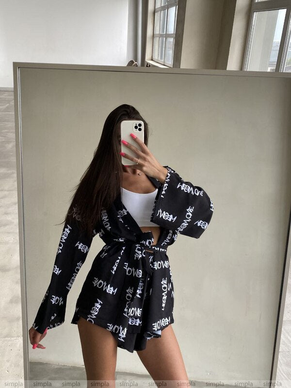 Person wearing a black outfit with white text pattern in front of a mirror.