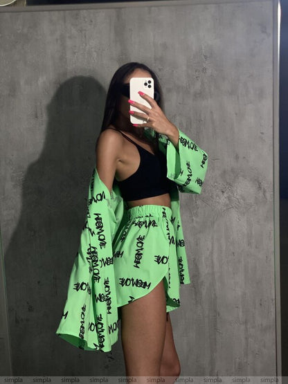 Person wearing a green kimono with black text against a gray wall.