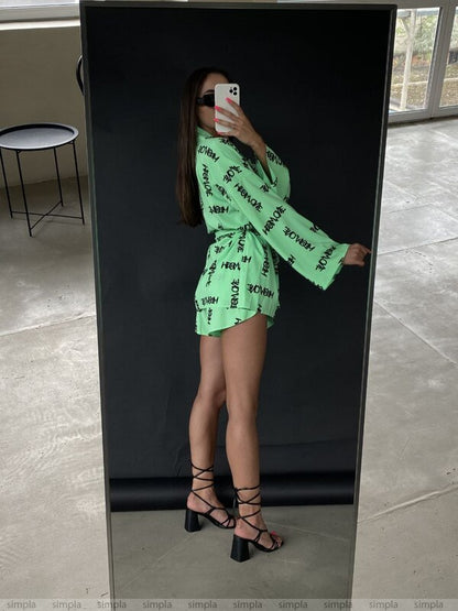 Person wearing a bright green outfit with text, standing in front of a mirror.