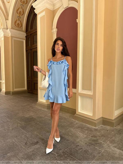 Woman in a light blue dress standing in an ornate hallway