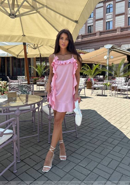 Woman in a pink dress standing under an umbrella in an outdoor setting