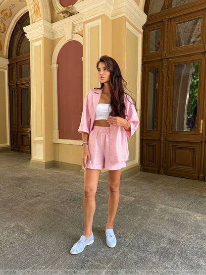 Woman in a pink outfit standing in front of an ornate building entrance.