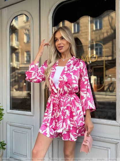 Woman wearing a pink floral dress standing in front of a door.