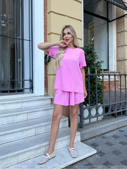Woman in a pink outfit standing on steps outside a building