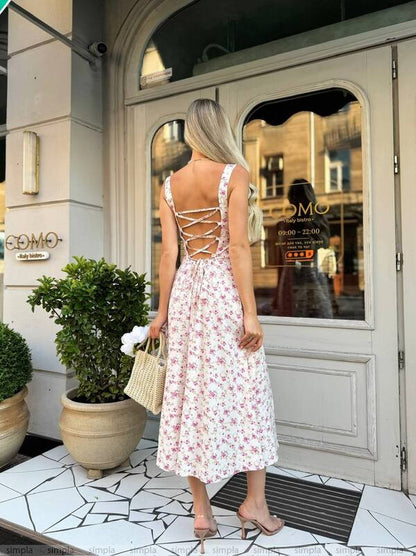Woman in a floral dress standing in front of a building entrance.