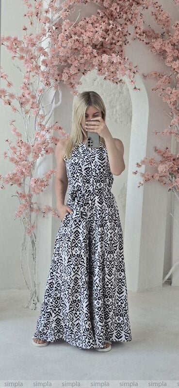 Woman wearing a black and white patterned dress standing in front of pink floral decorations.