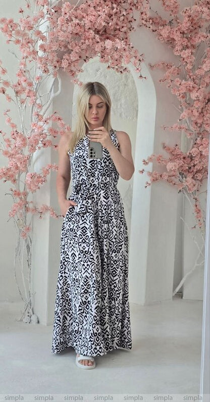 Woman in a black and white patterned dress standing in front of pink floral decorations.