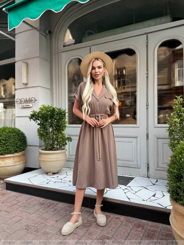 Woman in a brown dress standing in front of a building entrance with 'COMO' branding.