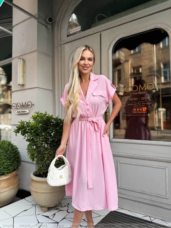 Woman in a pink dress standing outside a building with a 'COMO' sign.