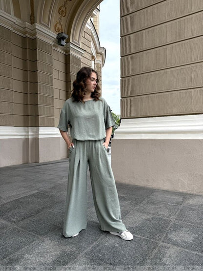 Woman in a green outfit standing in front of a classical building.
