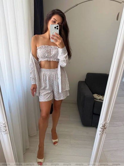 Woman taking a mirror selfie wearing a white outfit in a room with a gray sofa.