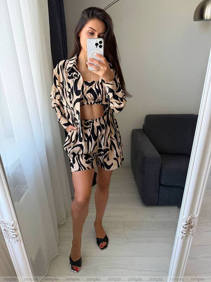 Woman taking a mirror selfie wearing a patterned outfit in a room with a gray sofa.