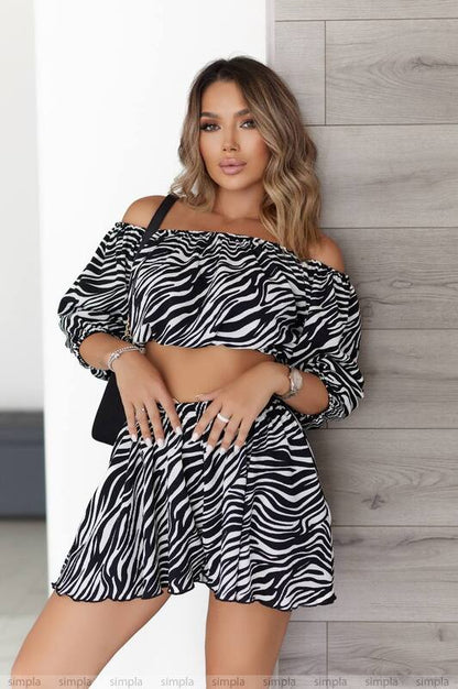 Woman wearing a zebra print outfit against a light wooden wall.
