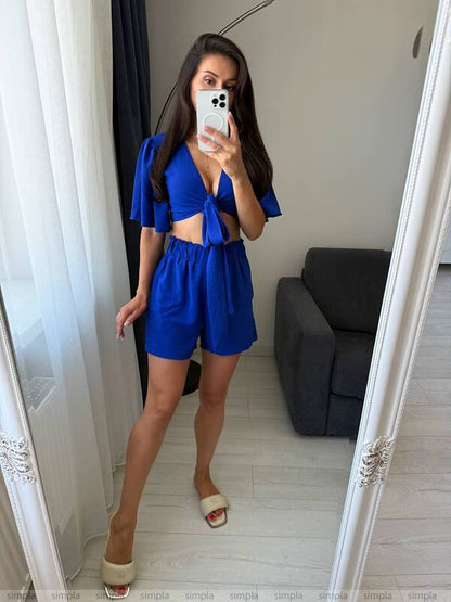 Woman taking a mirror selfie wearing a blue outfit in a room with a gray sofa.