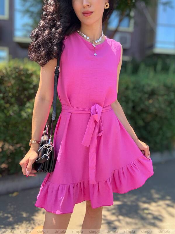 Woman wearing a pink dress outdoors with greenery in the background