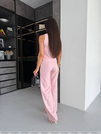 Woman in a pink outfit standing in a modern interior setting.