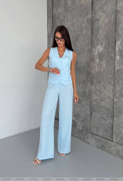 Woman wearing a light blue outfit against a gray wall.