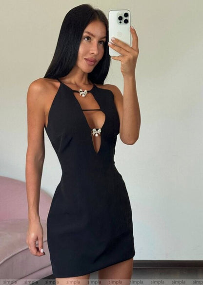 Woman taking a mirror selfie wearing a black dress with cut-out design.
