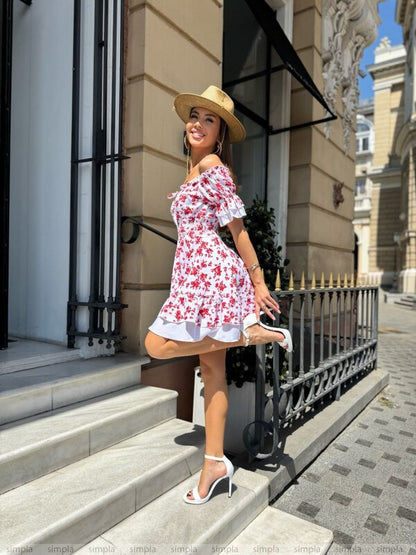 Woman in a floral dress and straw hat standing on steps in an urban setting