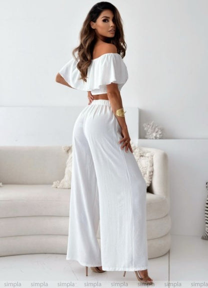 Woman wearing a white outfit in a minimalistic room.