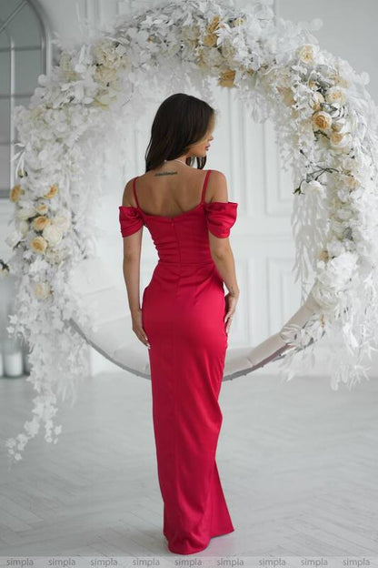 Woman in a red dress standing in front of a floral archway.