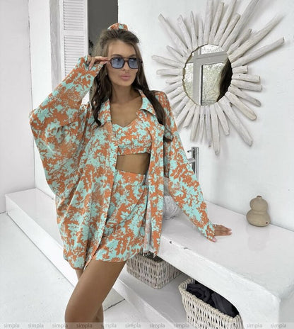 Woman in a floral outfit standing in a bright room with a decorative mirror.