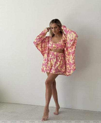 Woman wearing a pink floral outfit with a matching kimono-style jacket against a white background