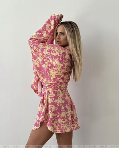 Woman wearing a pink and yellow floral dress against a plain background