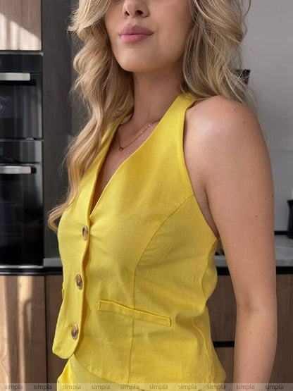 Woman wearing a yellow sleeveless top in a kitchen setting