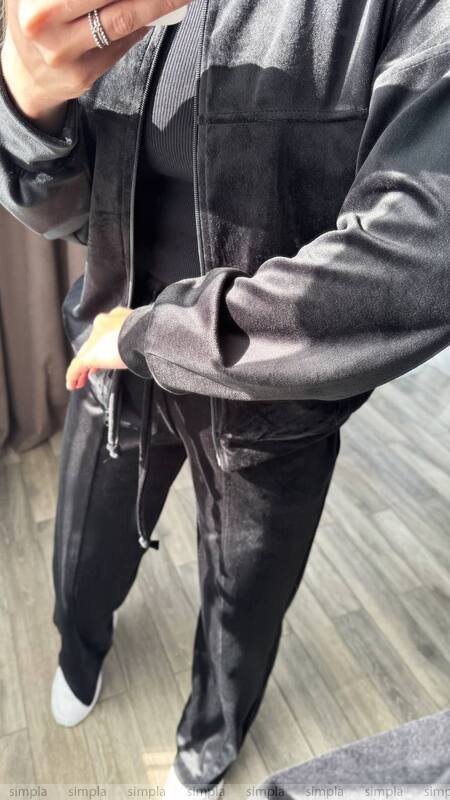 Person wearing a dark gray jacket and pants on a wooden floor.