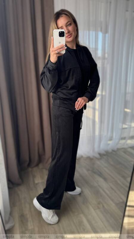 Person wearing a black outfit taking a mirror selfie.