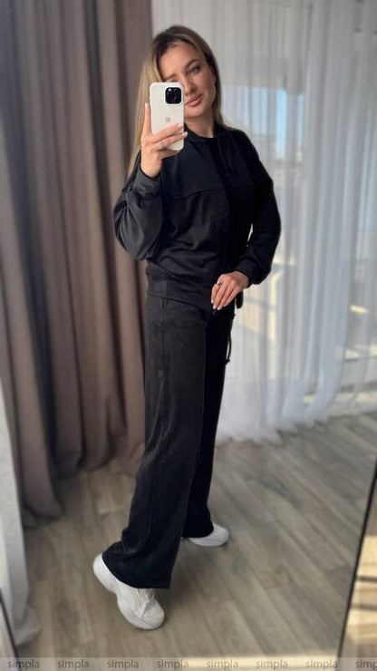 Person wearing a black outfit taking a mirror selfie.