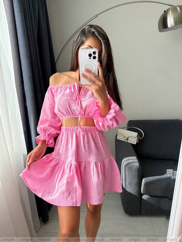 Woman wearing a pink off-shoulder dress taking a mirror selfie.