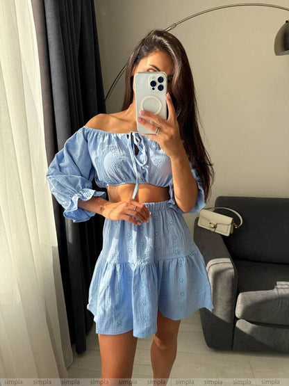 Woman taking a mirror selfie wearing a light blue outfit in a room.