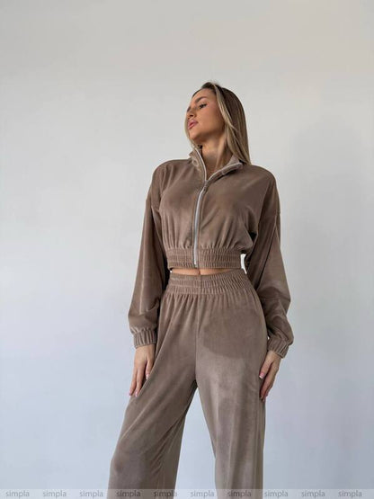 Woman wearing a brown tracksuit against a plain background
