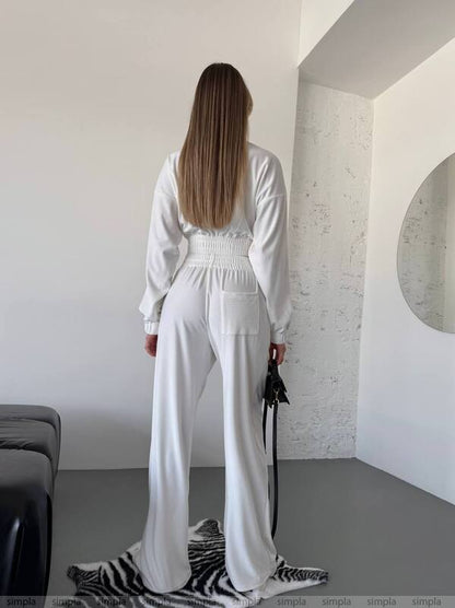 Person wearing a white outfit in a minimalistic room.