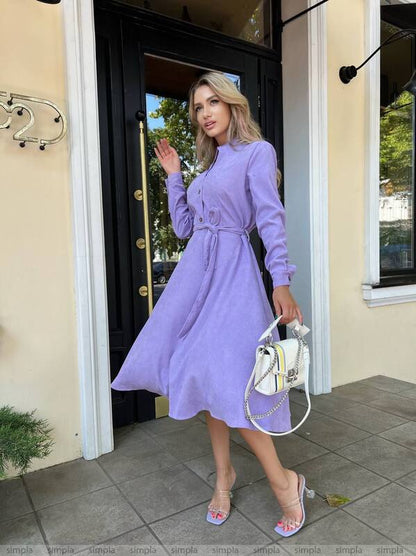 Woman in a purple dress standing outside a building
