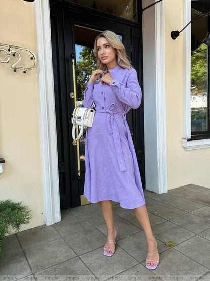 Woman in a purple dress standing outside a building