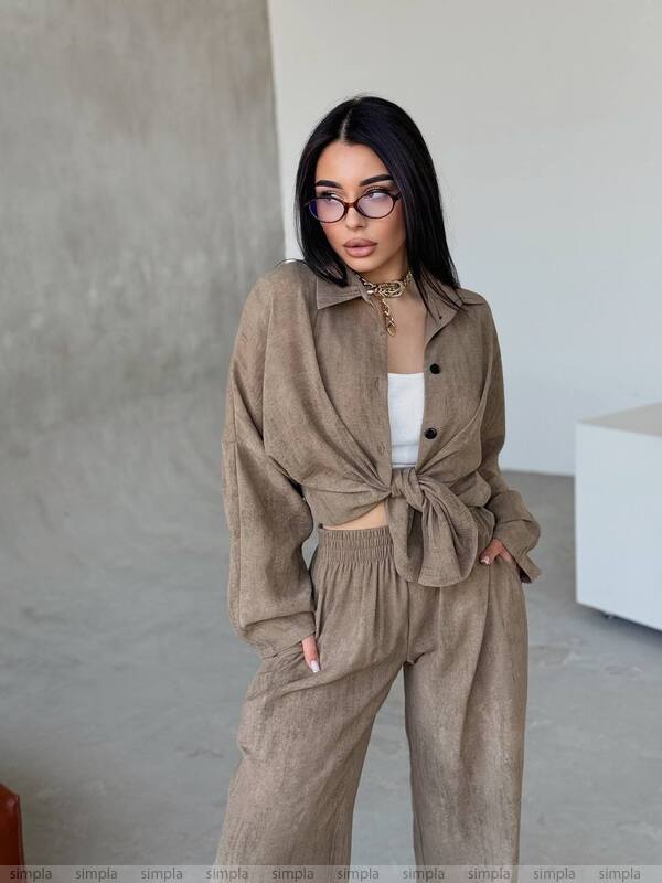Woman wearing a beige outfit with a white top against a neutral background