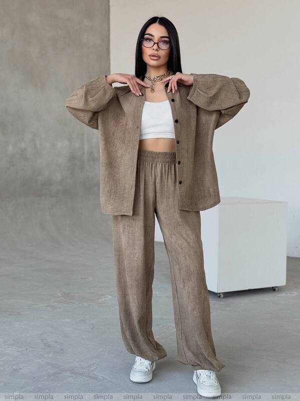 Woman wearing a beige outfit with a white top against a neutral background