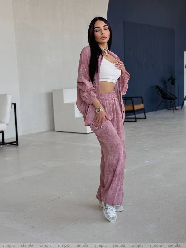 Woman in a pink tracksuit standing in a minimalistic room.