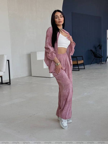 Woman in a pink tracksuit standing in a minimalistic room.