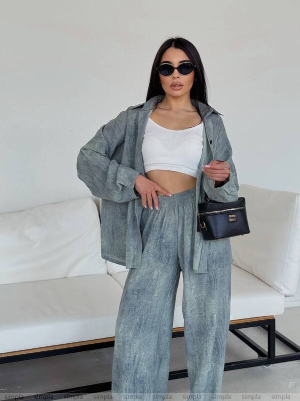 Woman in a gray outfit with sunglasses and a black handbag in a minimalistic setting