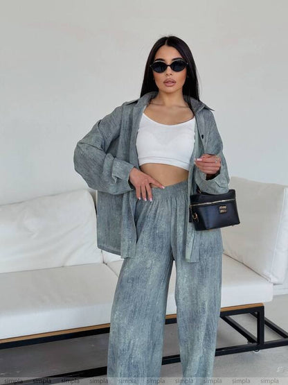 Woman in a gray outfit with sunglasses and a black handbag in a minimalistic setting