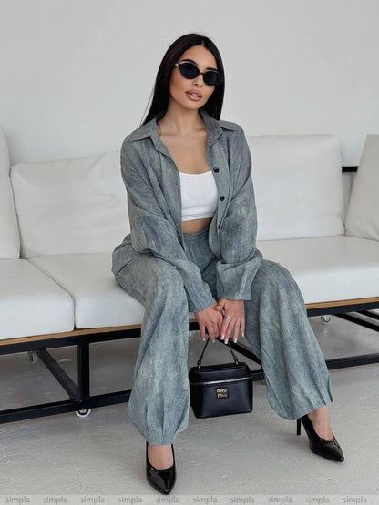 Woman in a gray outfit sitting on a white couch with a black handbag.
