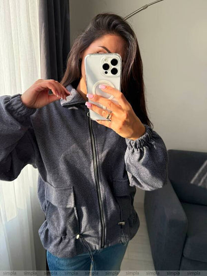 Person wearing a gray jacket taking a mirror selfie.